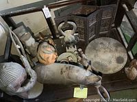 Overview of dust-covered bench top holding leather hippo, folding screen panels, decorative tray, carved statues