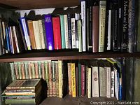 Books lined up on shelves. Scientific, historical, and literary books visible along with gardening encyclopedias and classics.