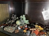 Shelf of assorted carved stone and ceramic animal figurines with jewelry box at left