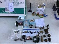 Overview of porcelain boxes, small enamel boxes, crystal and metal figurines displayed on table