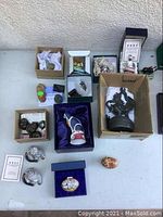 Overview of seven collectible items including porcelain cats, trinket boxes and bronze sculptures on table