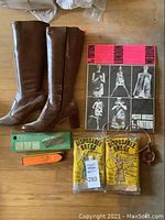 Overview of lot showing boots, poster dress sleeve, disposable dresses, massager, lint brush, necklace
