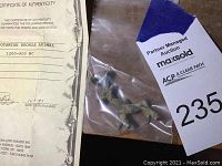 Certificate of authenticity printed and small bronze figurine in plastic bag with auction tag visible.