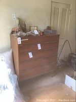 Front left perspective of wooden dresser showing all four drawers, metal handles, and tapered legs