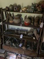 Four-tier dark wood shelving unit filled with decorative items, showing overall structure, drawers and wear