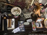 Top view of table showing various cat sculptures, decorative plate, watch box and pens