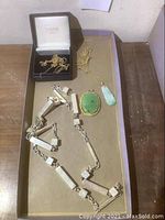 Tray containing sterling silver necklace, 14K gold chain with jade pendant, delicate gold chains in Warchal box, and loose jade cabochon pendant