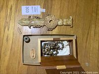 Overview of all five items on wood surface: stone cutter, disc weight, jewelry box with beads, fish fossil.