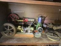 Two stationary model steam engines in red/green and gray/brass finish on a shelf