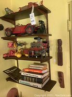 Four-tiered shelving unit with wooden airplane, red toy car, engine models, books