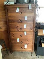 Full view of the tall brown wooden dresser, showing all six drawers and ring pull handles.