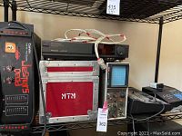 Shelf view showing Carvin amplifier at left, Panasonic VCR on top of red flight case, oscilloscope and two other devices on the right