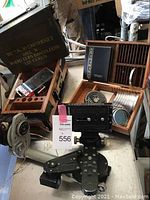 Overall view of fluid head, filter case, exposure selector, wooden rack and ammo box on metal table