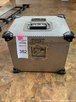 Closed aluminum flight case with reinforced corners, recessed front latch, top handle and lot tag attached