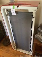 Folded treadmill showing red and white side panels and grey belt in upright storage position