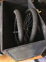 Two black 20-inch diameter wheels inside the black transport case showing tires and spokes