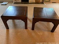 Pair of hardwood bunching tables shown side by side, square shape with panel design tops and carved legs