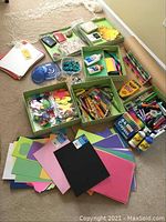 Complete assortment spread out showing colored papers, foam sheets, markers, crayons, glue, foam shapes, googly eyes, stamps, ink pads, colored pencils, storage boxes, and cotton string net with fish.