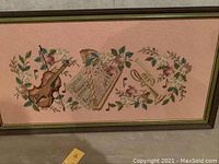 Full view of the framed crewel embroidery artwork with musical instruments and floral details on a pink background.