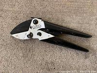 Closed view of CUTCO ratchet pruners showing logo and black handles on concrete floor.