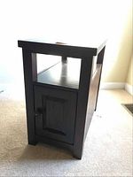 Side view of the hardwood end table showing cupboard with closed door, shelf, and smooth top surface.