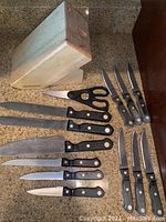 Photo showing full 13-piece Farberware kitchen knife set including the wooden block, kitchen scissors, and variety of knives with black handles and metal rivets.
