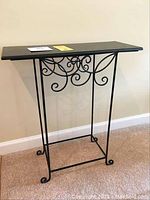 Side view of the black iron accent table showing decorative scrollwork on base and rectangular top.