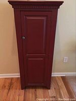 Front view of red jelly cupboard showing paneled door and metal knob