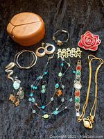 Photo showing the wooden ladybug-shaped jewelry box alongside various pieces of costume jewelry on a black background.