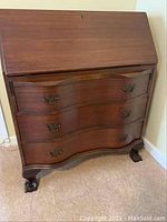 Mahogany secretary chest of drawers with drop-front desk closed, showing three curved drawers and claw feet