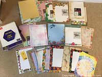 Overview of various specialty papers and card stock sheets in different patterns and colors spread out on the floor