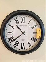 Front view of Sterling & Noble wall clock with black Roman numerals and black matte frame.