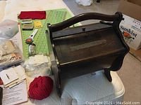 Vintage dark wood sewing box on white surface with sewing notions beside it.