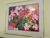 Framed watercolor print showing pink and red flowers with some green leaves in a pot, mounted with light matting and thin pink border.