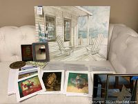 Large canvas print placed on couch with various small art prints and certificates displayed in front