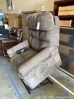 Front-left angle view of brown tweed lift chair with wired remote on seat