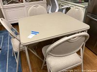 Square folding card table with four folding chairs arranged around