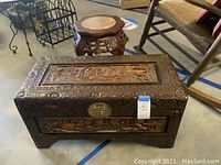 Overall view of carved wood trunk front and carved wooden table behind