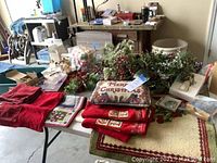 Photo of table with pillows, towels, artificial greenery with berries, and various Christmas decorations showing lot content.