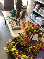 Photo of table showing floral wreaths and assorted country decor on white table