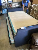 Front view of daybed with mattress on frame and trundle partially extended