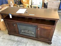 Front view of wood electric fireplace TV stand showing top, cabinets, and fireplace insert.