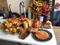 Full view of fall decor assortment on a table including florals, wreath, candles, and decorative plates and pumpkins