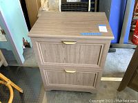 Full front view of the wood finish file cabinet showing two drawers with metal handles and flat top surface.