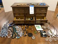 Overall view of wooden jewelry box with drawers open and assortment of jewelry items laid out on table