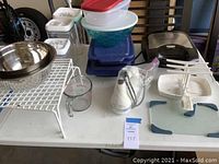 Overview of various kitchen storage containers, bowls, measuring cup, rack, and plastic organizing pieces laid out on table