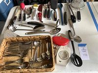 Wide view showing all flatware pieces and kitchen tools including the basket and tools on table for scale and contents identification