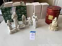Photo showing the Lenox Santa figurine in musical box and the 7 piece Nativity scene with all white figurines and their box packaging.