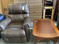 Brown vinyl recliner and wooden end table side by side, showing general condition and materials.