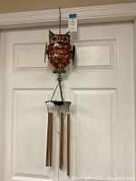 Full view of owl metal wind chime hanging on door, showing overall length and design including metal tubes.